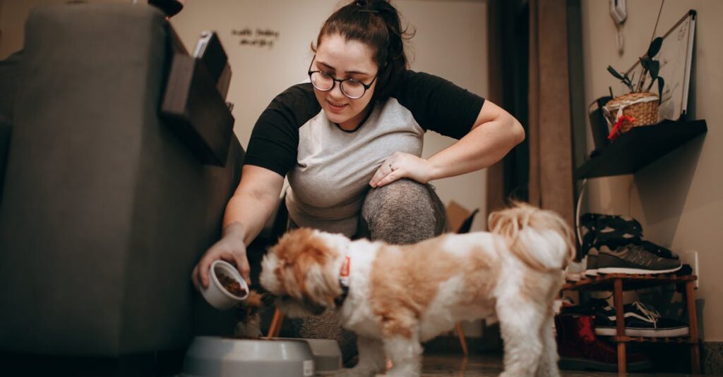 A woman in a casual outfit feeds her small dog indoors, creating a warm, cozy atmosphere.